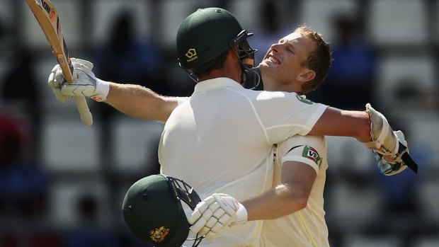 Australian Adam Voges celebrates with teammate Josh Hazlewood after reaching his maiden century in his debut Test during day two of the first Test match against the West Indies.