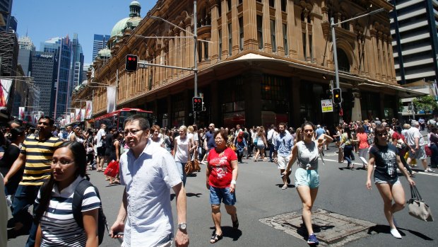 Pedestrians cross George Street in front of the Queen Victoria Building in Sydney.