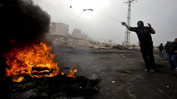 A Palestinian protester uses a slingshot to hurl stones at Israeli troops during clashes in Ramallah on Wednesday. 