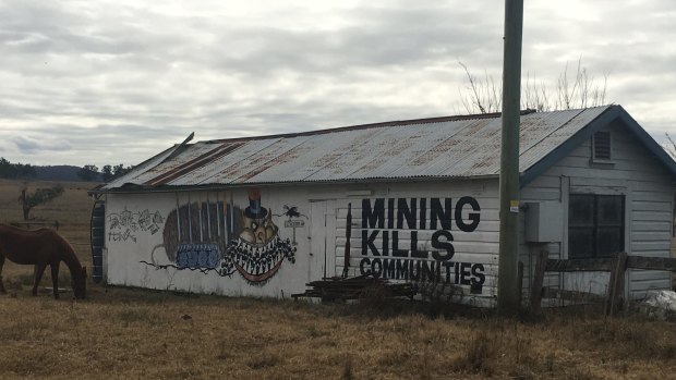 Anti-mine signs on the side of a shed beside the road into Gloucester.
