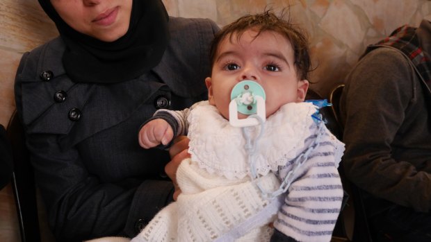 Four-month-old Abdullah waits with his mother at the care facility in Amman.