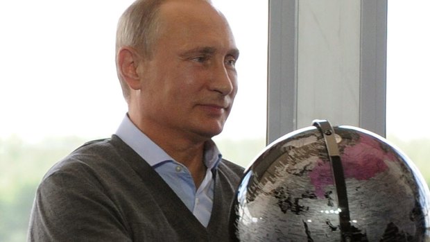Russian President Vladimir Putin holds a globe.