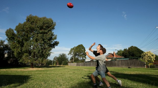 Boys play football on the Reservoir land Melbourne Water wants to rezone and sell. 