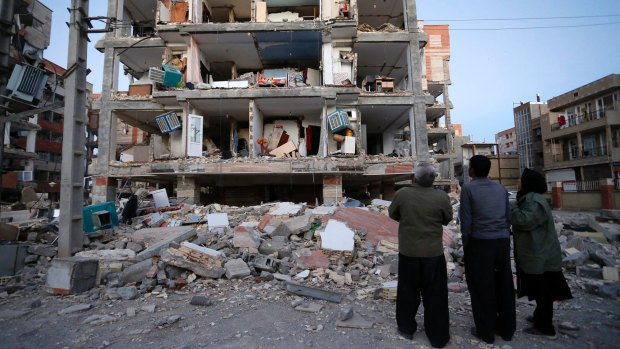 People look at destroyed buildings after an earthquake at the city of Sarpol-e-Zahab in western Iran.