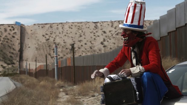 A protester dressed as a diabolical version of Uncle Sam holds a suitcase full of money at the US border fence in Ciudad Juarez, Mexico, last month.  