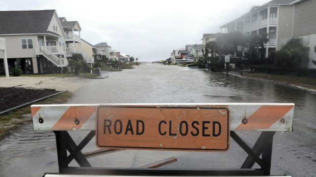A road closed barricade blocks a flooded street in Ocean Isle Beach, North Carolina on Sunday.