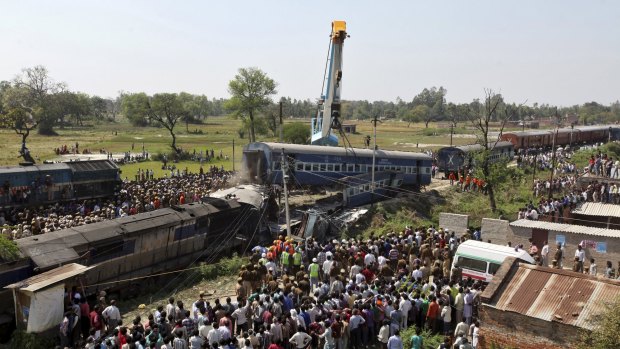 Onlookers stand at the site of a train accident at Rae Bareli district. At least 30 people were killed and 50 injured when an express train overshot a railway signal and some carriages went off the rails, officials said. 