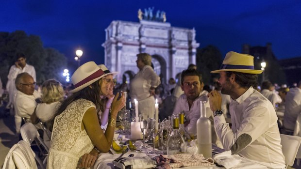 Participants dressed in white take part in Diner en Blanc, or White Dinner, backdropped by the Arc de Triomphe in Paris on Thursday.