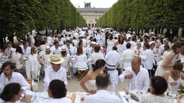 Participants dressed in white enjoy their meal at the gardens of the Palais-Royal in Paris on Thursday.