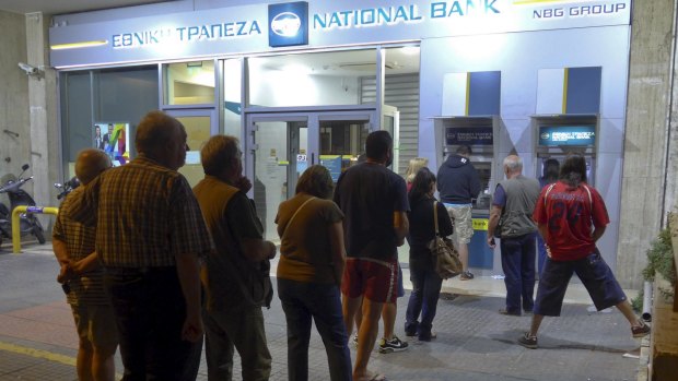 People line up at an ATM outside a National Bank branch in Athens, Greece.