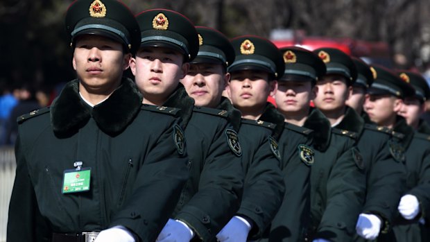 Paramilitary police officers march past the Great Hall of the People.