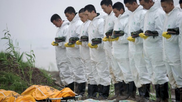 Rescue workers pay respects to victims after a cruise ship sank at the Jianli section of the Yangtze River in China on Monday night.