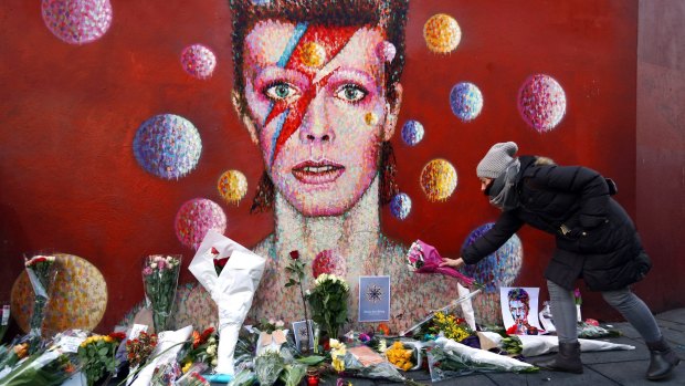 A woman leaves flowers beneath a mural of David Bowie in Brixton in January.