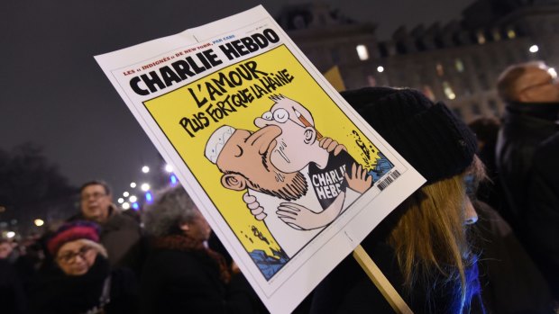 A woman holds a Charlie Hebdo's front page reading "Love stronger than hate" during a gathering at the Place de la Republique (Republic square) in Paris.