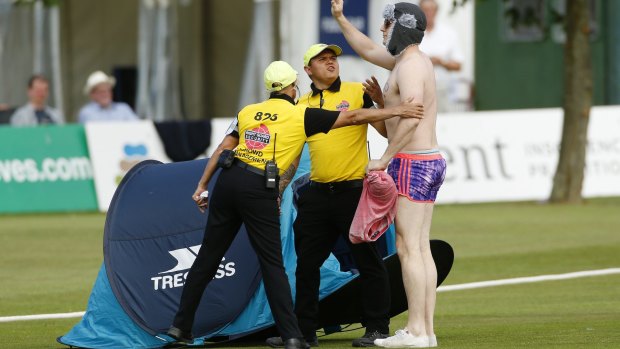 Stewards attempt to remove a spectator who invaded the pitch with a tent.