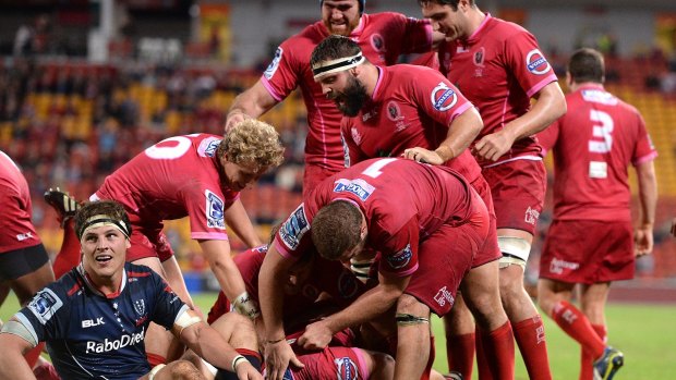 Liam Gill of the Reds is congratulated by team mates after scoring a try against the Melbourne Rebels.