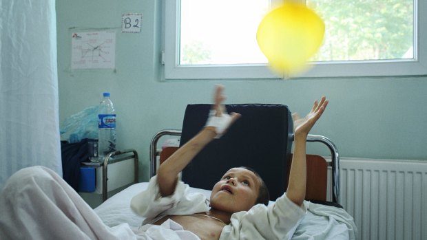 A young patient, recovering from a severe shrapnel wound, playing with a balloon.