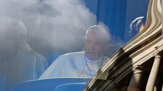 Pope Francis sits on a bus as the Vatican's Bernini colonnade is reflected on the windscreen on Sunday. 