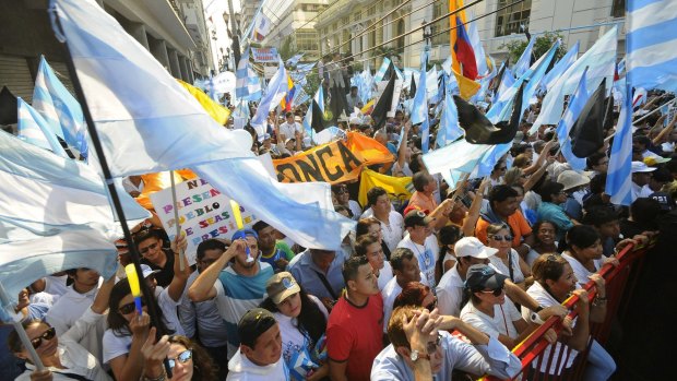 Hundreds of people gather during a protest against the government in downtown Guayaquil, Ecuador, last week. President Rafael Correa eased a proposed redistribution of wealth to avoid an escalation of conflict with the business sector.