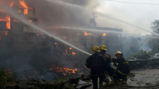 Firemen try to extinguish a fire that engulfed a slum area in Manila on January 1, 2015.