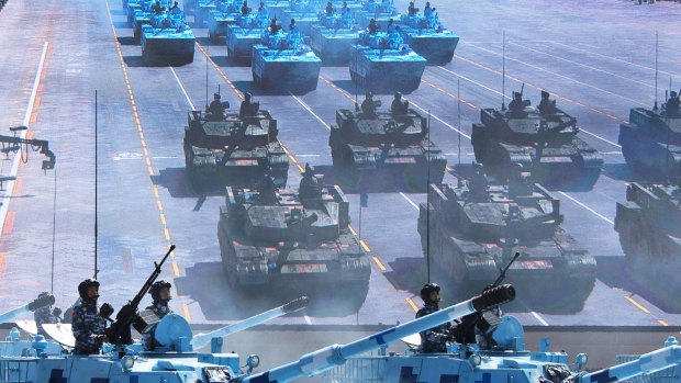 Chinese soldiers ride in tanks as they pass a large screen on Tiananmen Square. 