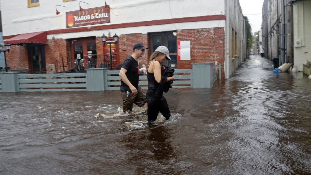 Residents walk along flooded Water Street in Wilmington, North Carolina. 