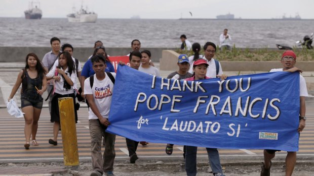 Environmental activists carry a banner as they march towards a Roman Catholic church to coincide with Pope Francis' encyclical on climate change on Thursday in Manila, Philippines.