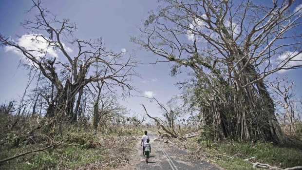Children walk down a devastated main road on north side of the main island of Efate.