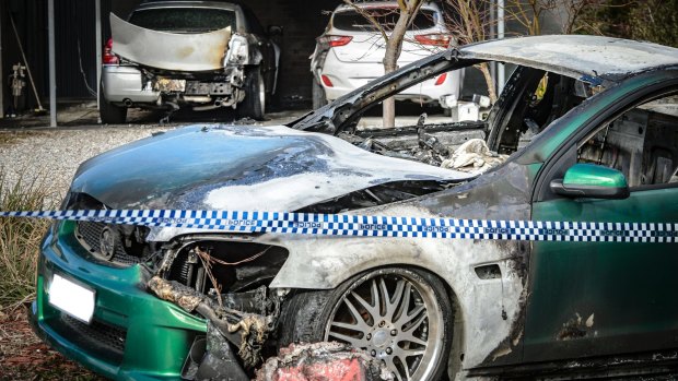 Police examine a property in Kambah after shots were fired and vehicles set alight on Friday morning in what police are describing as the latest incident in an ongoing bikie feud.