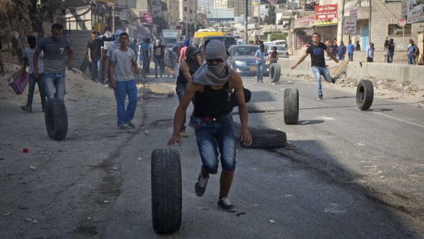 Palestinians roll tyres during clashes with Israeli troops at the Qalandia checkpoint between Jerusalem and the occupied West Bank city of Ramallah.