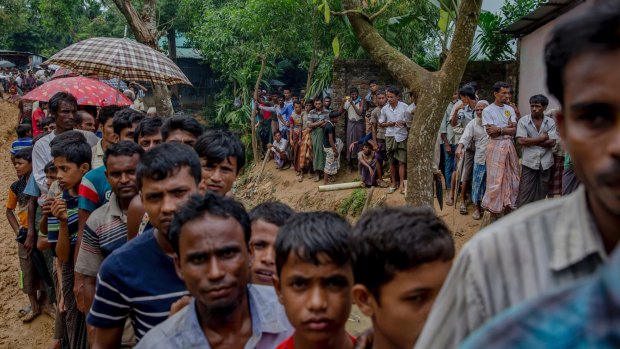 Rohingya men wait to collect building material for shelters at a refugee camp in Bangladesh.