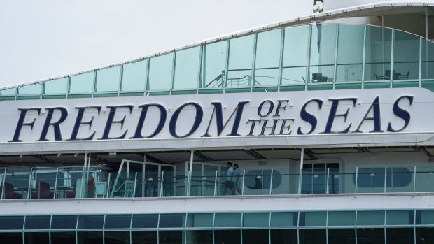 Royal Caribbean employee volunteers walk on the deck of the Freedom of the Seas cruise ship before sailing.