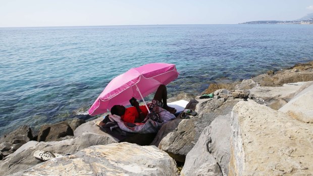 A picture taken on Monday in Ventimiglia shows a migrant resting near the Italian-French border post, where a group of migrants has been camping since being denied entry into France. 