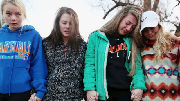 Students Brooklyn Boyce, left, and Katlyn Gamble cry as they hold hands with other Marshall County High School classmates during a prayer vigil for their classmates.