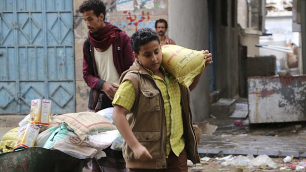 A boy carries a bag of sugar to his family during a food distribution by Yemeni volunteers in Taiz, Yemen, on Wednesday.