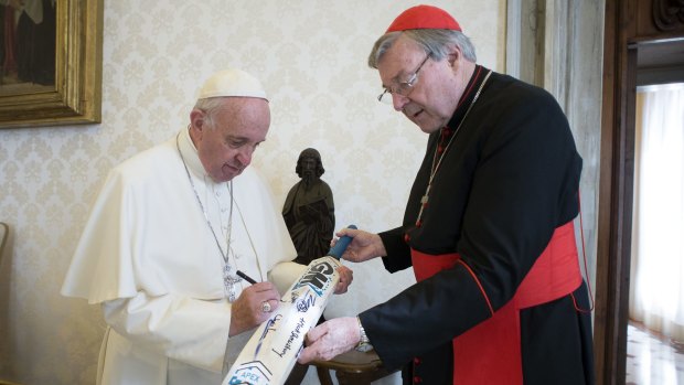 Pope Francis signs a cricket bat he received from Cardinal George Pell at the Vatican. Pell's dicky heart prevents him from fronting up to answer questions about abuse by Catholic church personnel. 