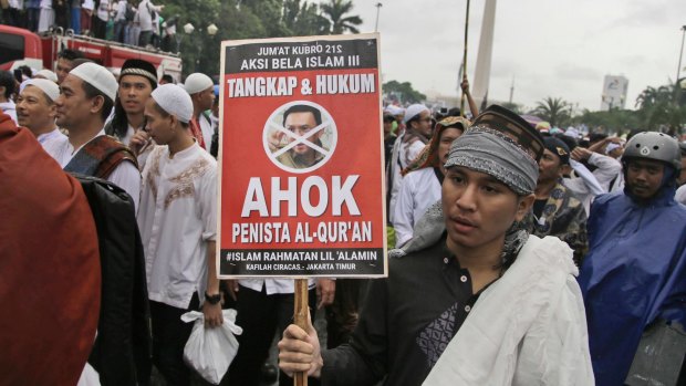 A protester holds a poster during a rally against Jakarta Governor Basuki "Ahok" Tjahaja Purnama, a Christian, over his alleged insult to the Koran.