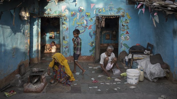 Sitting outside their Rajasthani home a family prepares a meal at dusk. The family's home is inside a small slum in Vasant Vihar, an exclusive suburb of New Delhi, India.