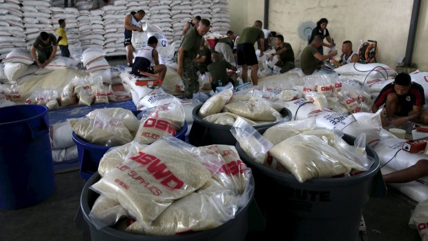 Members of the Armed Forces of the Philippines help out volunteers repacking food rations for victims of Typhoon Noul.