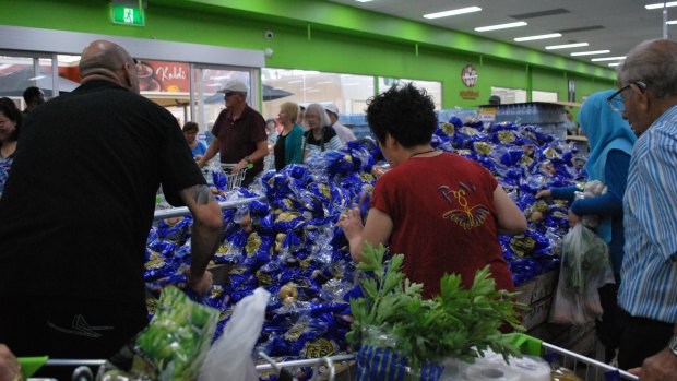 Shoppers vie for the bag of free potatoes that might, just might, contain 1.1 instead of just 1 kilogram, despite staff's earnest assurances that they are all the same. 