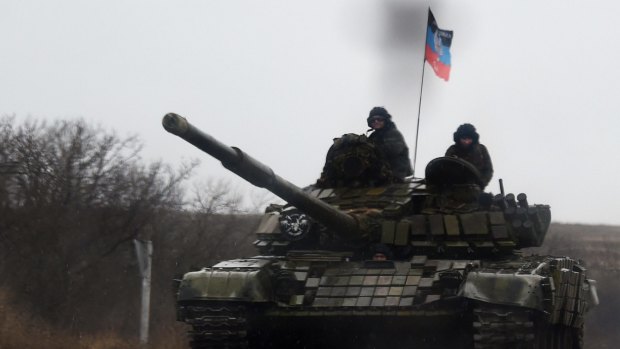 A tank crew displays the "Republic of Donetsk" flag as they drive along the road near the eastern Ukrainian city of Donetsk.