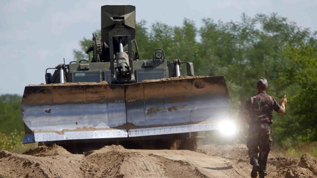 Hungarian army soldiers use a bulldozer as they prepare the land to build a fence along the Hungarian border with Serbia near Morahalom, Hungary.