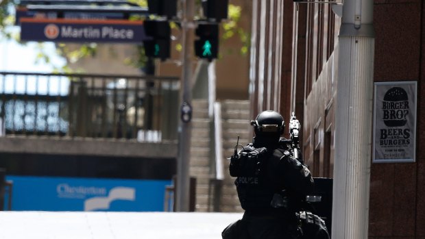 A police officer points his weapon towards the siege at Lindt Cafe in Martin Place