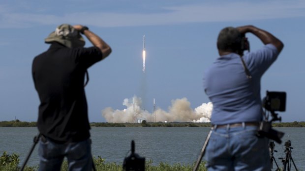 Photographers capture the unmanned SpaceX Falcon 9 rocket with Dragon as it lifts off from launch pad 40 at the Cape Canaveral Air Force Station in Florida on Tuesday.