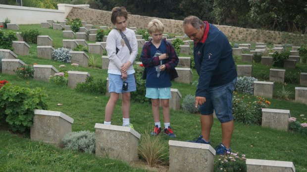 Guide Aykut tells Jake, 12, (left) and Sebbie, 10, the story of one of many Australians buried in a cemetery.
