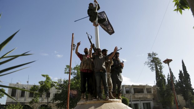 A member of al-Qaeda's Nusra Front climbs on a pole to hang the Nusra flag at a central square in Ariha, after a coalition of insurgent groups seized the area in Idlib province last week.
