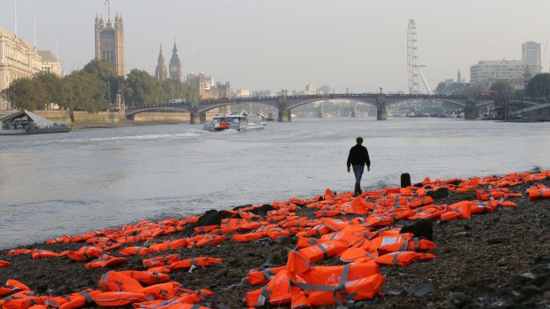 A man walks among hundreds of lifejackets scattered by UK charities ActionAid and Islamic Relief on the bank of the Thames, London, to highlight the plight of refugees.