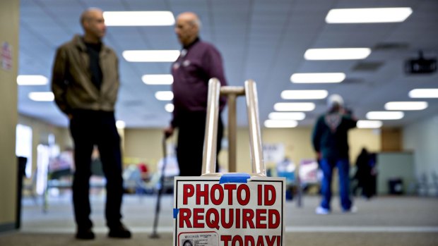 A "Photo ID Required Today" sign hangs at the entrance of a polling location during the presidential primary vote in Wisconsin in April. 