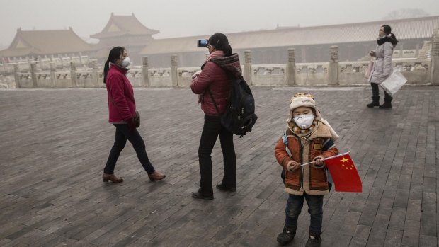 A Chinese boy  wears a mask as protection from the pollution as he stands with a China flag in the Forbidden City in Bejing on Tuesday. 