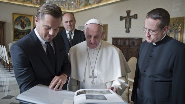 Show and tell ... Pope Francis browses through the book of paintings with Leonardo Di Caprio.